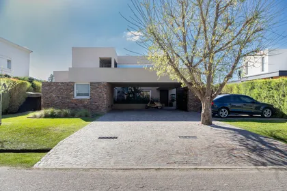 Casa moderna con fachada de piedra y árbol grande — proyecto Campo grande IV, por Juarez-Fevre Estudio de Arquitectura , en Buenos Aires