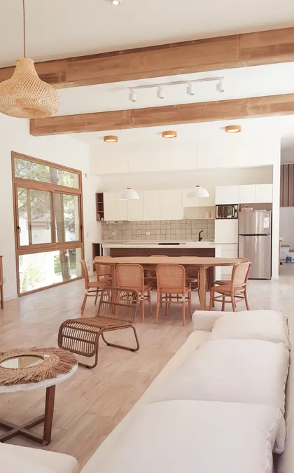Cocina y sala de estar integradas con vigas de madera y mucha luz — proyecto Casa NF, por TAVA Coop, en Pinamar