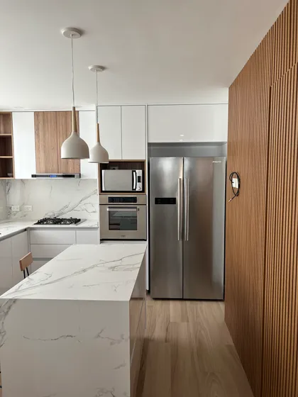Cocina moderna con isla y pared de lamas de madera — proyecto DEPTO SCA , por Estudio Grupo 32, en Buenos Aires