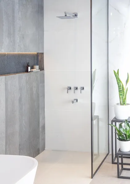 baño moderno con paredes de piedra, ducha y bañera exenta — proyecto Showroom para Vite Porcellanatos (Buenos Aires) German Salas arquitecto, por German Salas arquitectura - San Is