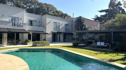 Piscina moderna rodeada de vegetación y fachada blanca — proyecto Villa Isidro Hotel Boutique & Spa, por Hermann Arquitectos, en San Isidro