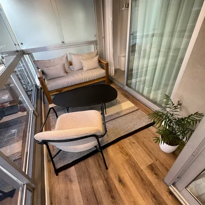 Balcón moderno con sofá beige, mesa negra y plantas — proyecto Salguero I, por MDBK Arquitectura, en Palermo