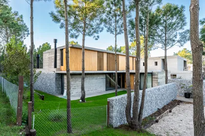Casa moderna con base de piedra y detalles de madera en bosque — proyecto casa la huella, por Guerrero Arquitectos, en Pinamar