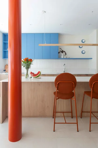 Cocina moderna con isla de madera, sillas naranjas y gabinetes azules — proyecto Grecia, por Bouré Studio, en Núñez