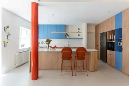 Cocina moderna con isla ovalada de madera y pilar naranja — proyecto Grecia, por Bouré Studio, en Núñez