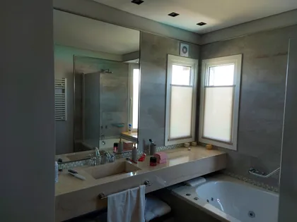 Baño moderno con doble lavabo, espejo grande y paredes de piedra — proyecto Haras Sta. Maria, por CM Espacio & Arquitectura, en Belén de Escobar