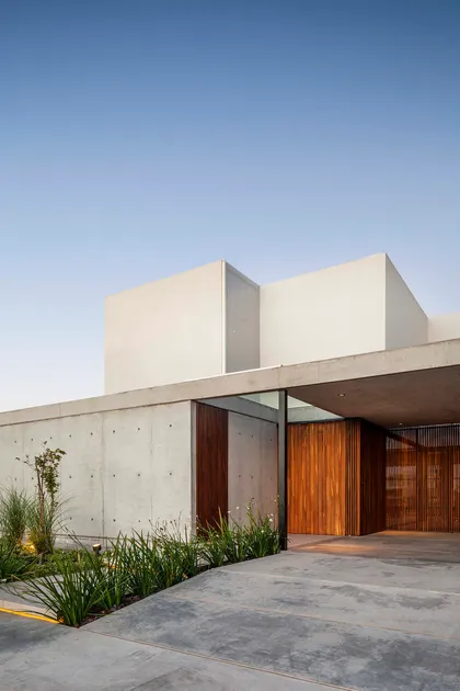 Fachada moderna con hormigón crudo y madera natural — proyecto CASA J2M, por GMARQ, en Belén de Escobar