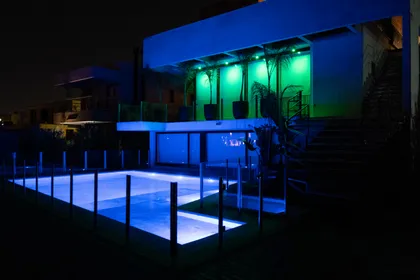 Piscina moderna iluminada de noche con luces azules — proyecto Casa Pomelo, por FeelX Tecnología SRL, en Canning
