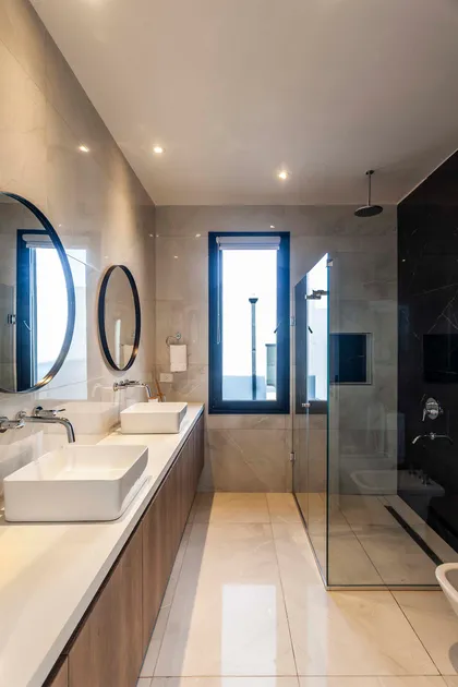 Baño moderno con doble lavabo, paredes de mármol, ducha de cristal y buena iluminación — proyecto Castaños, por GO arquitectos , en Rincón de Milberg