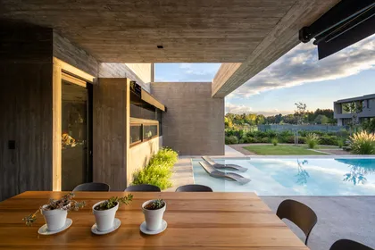 Quincho moderno de hormigón con pileta y vegetación exuberante — proyecto Casa Tres Patios, por Besonías Almeida arquitectos, en Pilar