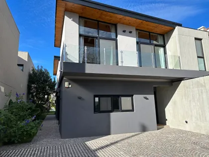 Fachada moderna con concreto, madera y amplios ventanales — proyecto Casa Belen, por Arq. Damian Fainzilber, en San Isidro
