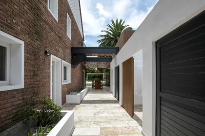 fachada de casa moderna con ladrillos y pérgola — proyecto Obra La Posta, por Arq. Lourdes Yarade Saravia, en Pilar