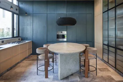Cocina moderna con mesa de piedra, barra y paredes azules — proyecto Casa Órbita, por Estudio PK, en Nordelta