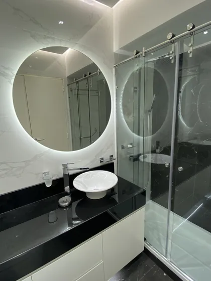 Baño minimalista con espejo circular iluminado y ducha vidriada — proyecto PH HOLMBERG, por Estudio Grupo 32, en CABA