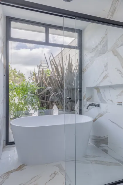 Bano minimalista con banera redonda blanca y marmol de piso a techo — proyecto RLT, por Buriti Arquitetura
