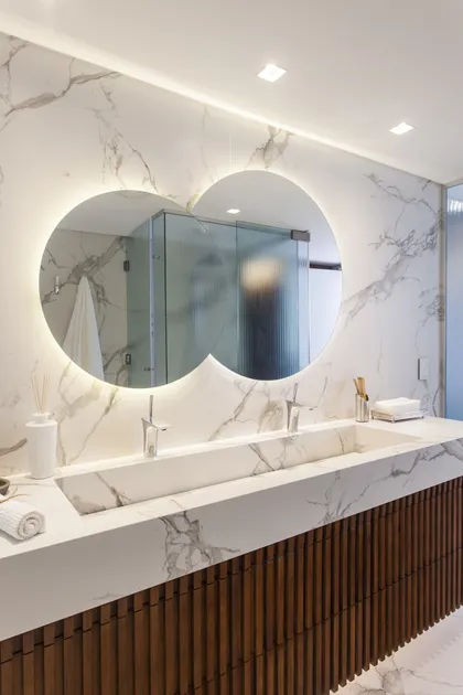 Baño moderno de lujo con espejo curvo retroiluminado y bacha de mármol — proyecto Pacífico BRT, por Vanguarda Arquitectos, en CABA