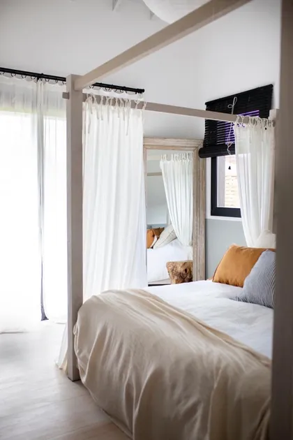 Dormitorio con cama doble estructura madera y cortinas blancas — proyecto JI 103, por Estudio Diez Muzzio
