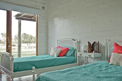 dormitorio rústico con dos camas gemelas y vista al campo — proyecto Chacra Pilará, por Mazzinghi Sanchez, en Pilará