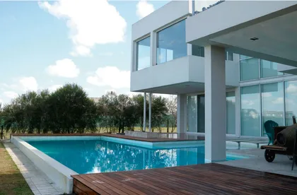 Impresionante piscina moderna rodeada de deck de madera en entorno rural — proyecto CASA GOLF I, por Alejandra Pan Arquitectura, en Nordelta