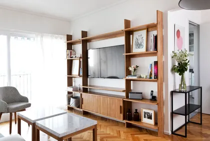 Living moderno con estanterías modulares de madera y sillón gris — proyecto Proyecto Alfaro, por URBANO estudio, en Martínez