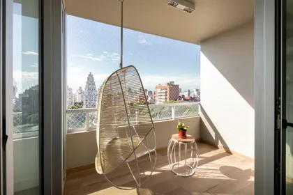 Balcón moderno con silla colgante de ratán y vista urbana — proyecto Mirabilia, por Estudio Basa, en Buenos Aires