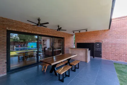 Comedor exterior con ladrillos expuestos y parrilla integrada — proyecto VIVIENDA L.L, por Lorenabusquetsarquitectura, en Córdoba
