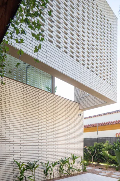 Fachada moderna de ladrillo blanco y beige con patrones perforados — proyecto Casa Magnolia, por Estudio PK, en San Isidro