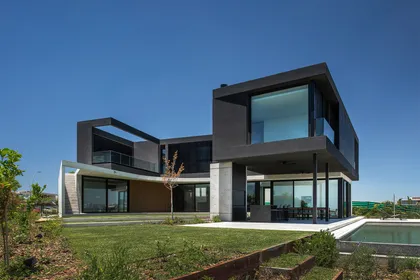 Casa moderna con volúmenes geométricos y grandes ventanales — proyecto CASA MUELLES, por GMARQ, en Escobar