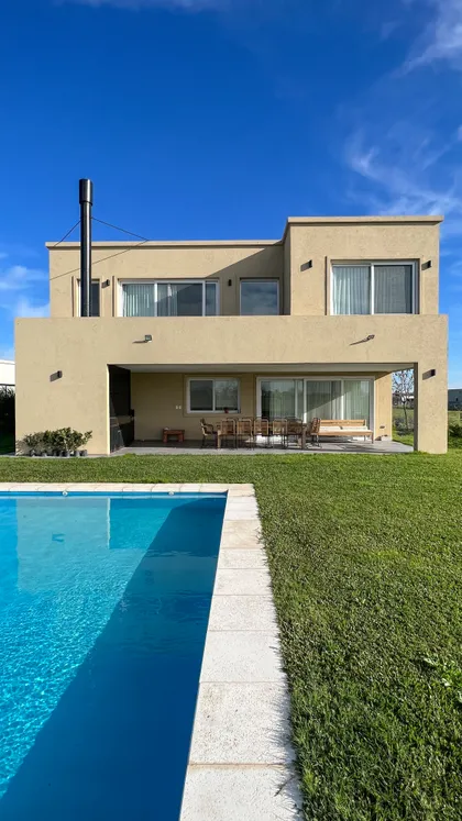 Casa moderna con pileta, fachada beige y gran galería con vista — proyecto Casa Hipico, por RY Construir Estudio, en Pilar