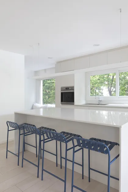 Cocina moderna con isla, bancos azules y ventanales amplios — proyecto Reforma Isla del Sol, por Estudio YME, en Rincón de Milberg