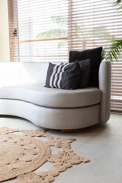 Sofá curvo beige con alfombra redonda de yute y luz natural — proyecto Casa Canning, por Gaby Alfonso, en Canning