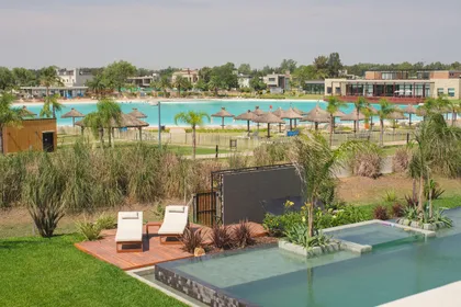 Piscina infinita moderna con área de estar exterior rodeada de vegetación exuberante — proyecto Casa Durazno, por FeelX Tecnología SRL, en Canning