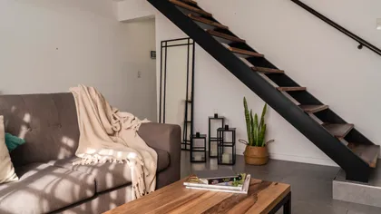 Living moderno con escalera flotante y sofá modular — proyecto Vivienda Mari y Lean, por Jeitinho Estudió Creativo, en La Plata