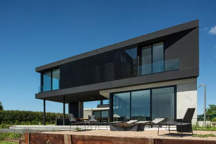 fachada moderna con contraste de materiales y grandes ventanales — proyecto CASA MUELLES, por GMARQ, en Escobar