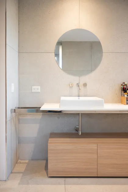 Baño moderno minimalista con espejo redondo y mueble de madera clara — proyecto Campo grande I, por Juarez-Fevre Estudio de Arquitectura , en Pilar