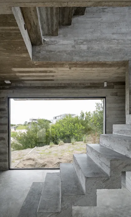 Escalera de hormigón visto con vista al paisaje y ventanal — proyecto Casa Golf, por Luciano Kruk