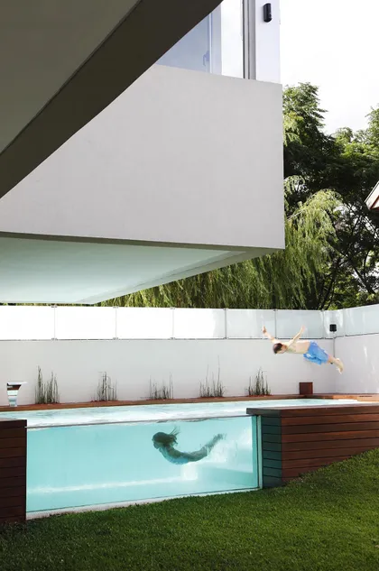 Casa moderna con piscina de cristal y gente nadando — proyecto Devoto, por Remy Arquitectos, en CABA
