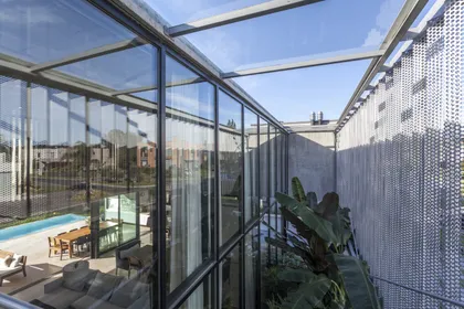 Terraza moderna con paredes de vidrio y pantalla metálica — proyecto Casa ADR, por Jorgelina Tortorici & asoc., en B1846 Adrogué