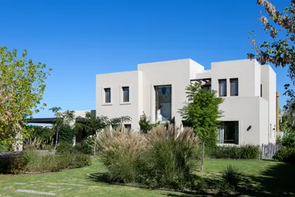 Fachada moderna con grandes ventanales y vegetación exuberante — proyecto Pilara I, por Escalante Vela Arquitectos, en Pilará