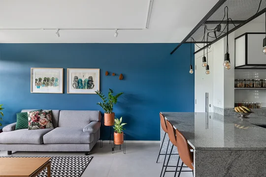 Living moderno con pared azul, sofá gris y cocina integrada al fondo — proyecto Apartamento 415N, por Coda Arquitetos