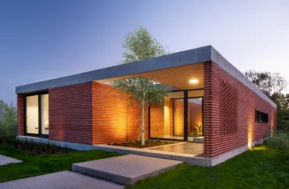 Casa moderna con fachada de ladrillo y madera, patio interior y techo voladizo — proyecto Casa FLOIG, por V2 Arquitectos, en Villa Elisa