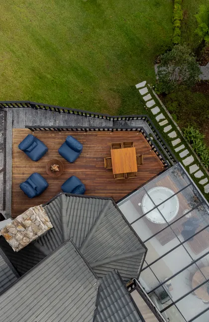 Terraza moderna con sillones azules, mesa de madera y bañera bajo techo de vidrio — proyecto Campos do Jordão, por SABRINA SALLES, en São Paulo