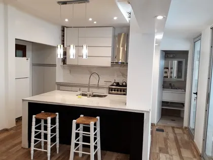 Cocina y comedor modernos con isla central y luces colgantes — proyecto Remodelación cocina 8, por Zima Arquitectura, en La Plata