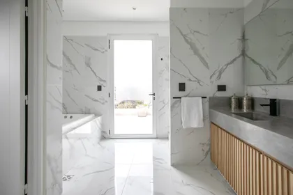 Baño moderno con mármol blanco y mueble de madera — proyecto Obra El Encuentro, por Arq. Lourdes Yarade Saravia, en Benavidez