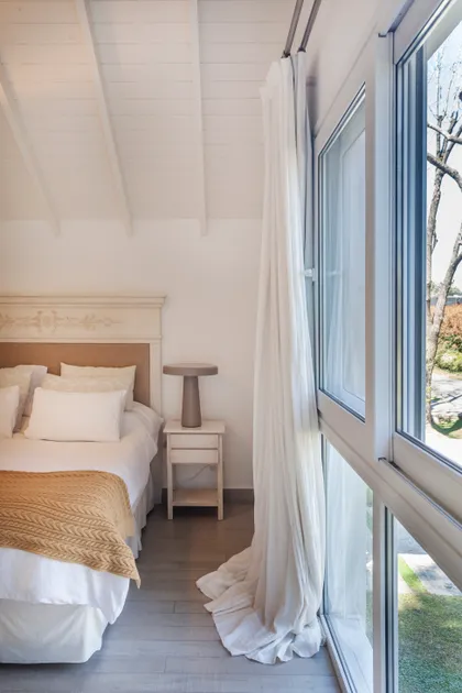 Dormitorio con techo a dos aguas de madera y gran ventana — proyecto Highland, por Lala Loviscek arquitecta, en Pilar