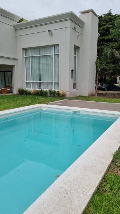 Casa moderna con piscina azul y fachada de concreto blanco — proyecto Casa estilo clásico moderno, por Vidal Bianchi arquitectura, en Pilar