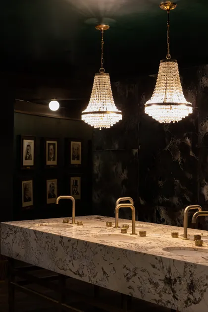 Baño comercial con dos arañas de cristal y tocador de mármol — proyecto PRESIDENTE BAR HIPODROMO, por AB ARQUITECTURA, en San Isidro