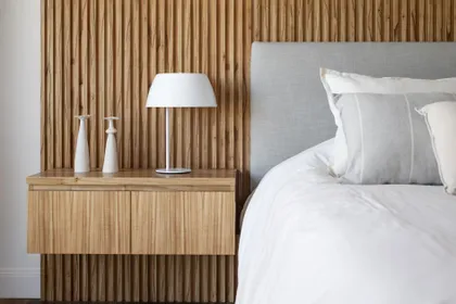 Dormitorio moderno con pared de lamas de madera y mesa de noche de diseño — proyecto Lacroze, por Estudio Basa, en CABA