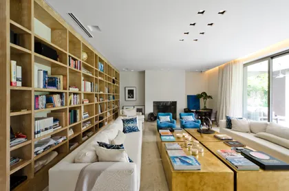 Living moderno con estanterías de madera hasta el techo y sofá seccional — proyecto Casa H, por Estudio Dado, en Belgrano