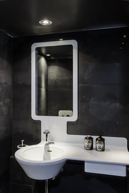 Baño moderno con lavabo integrado, espejo grande y paredes de piedra oscura — proyecto Piso en Belgrano, por Gutman+Lehrer Arquitectas, en Belgrano